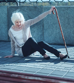Woman lying on the ground holding a cane