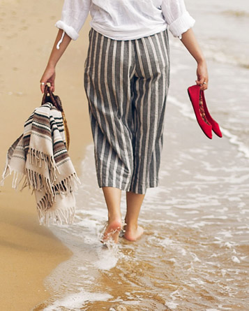 A woman walking with her bare feet in the water on the beach